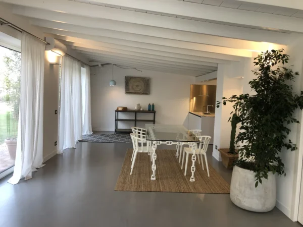 Dining area with glass table and white beams in apartment ARA