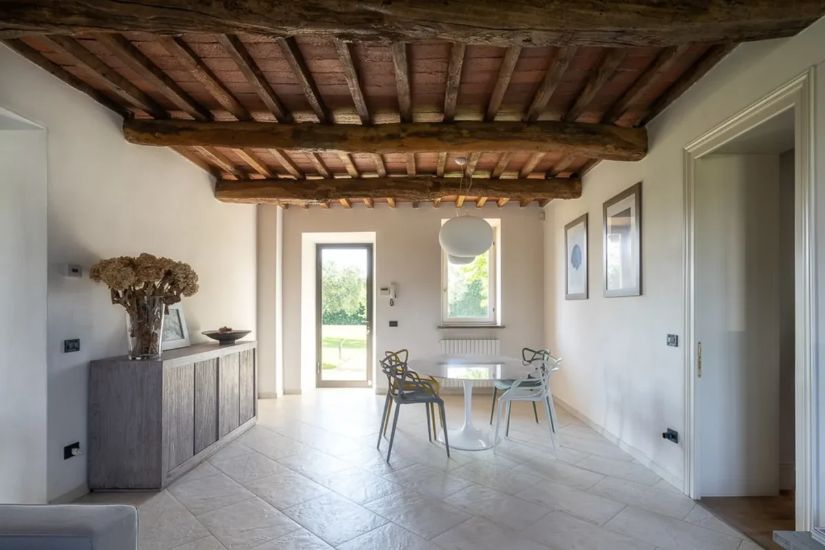 Dining room of the villa apartment ARABELLA in Pietrasanta, with a round marble table under original wooden beams