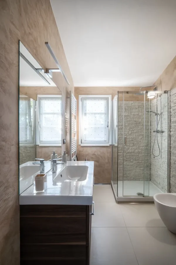 Bathroom with sand-coloured plaster walls, walk-in shower and double basin