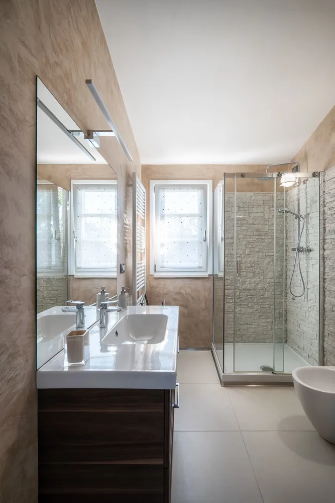 Bathroom with sand-coloured plaster walls, stone walk-in shower and double basin