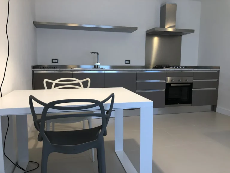 Kitchen with steel shelf, extractor hood and designer chairs