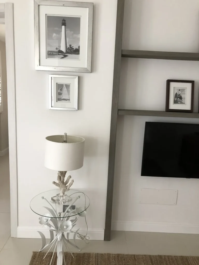 Seaside prints of a lighthouse and a sailing boat above a coral table lamp
