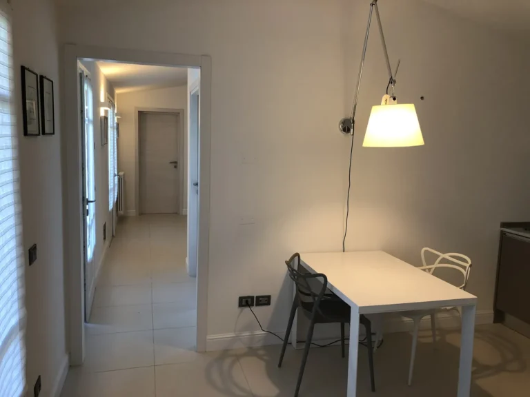 Dining table under an arching lamp, with the hallway beyond