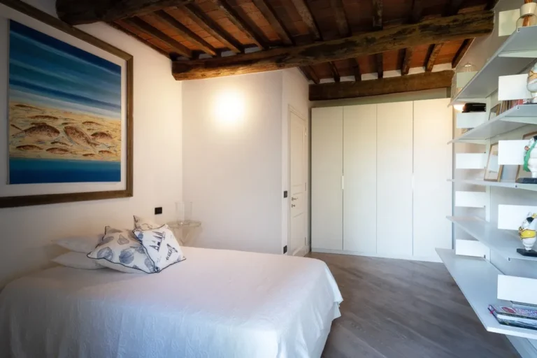 Bedroom with sea painting, white wardrobe and open shelving