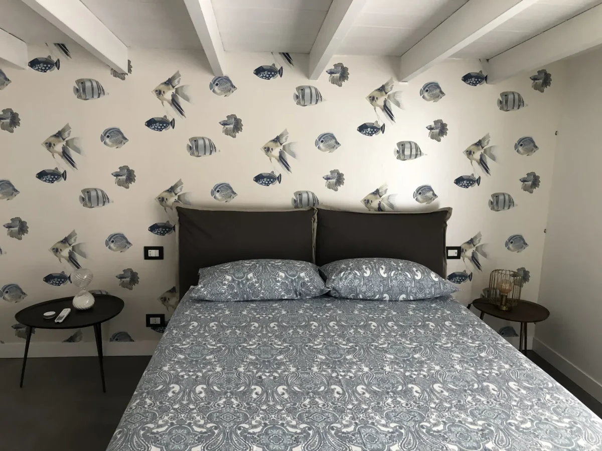 Double bedroom of the BELLA apartment by the pool, with tropical fish wallpaper and blue paisley linen