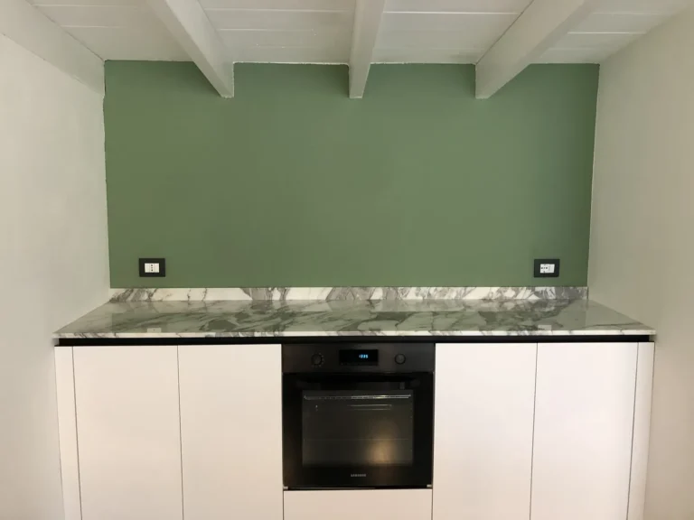 Sage-green wall above a white marble worktop and built-in oven