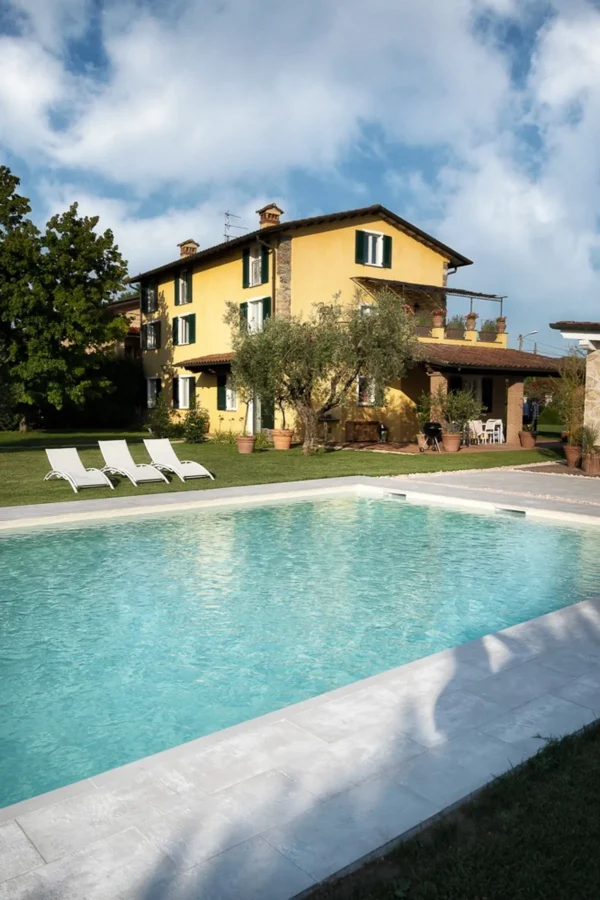 The yellow Tuscan villa with holiday apartments in Pietrasanta, overlooking the pool and the lawn